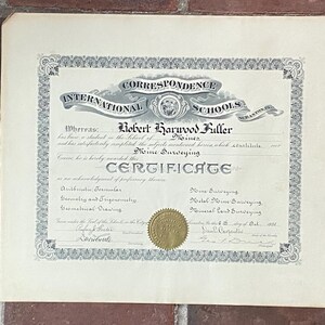 May include: A vintage International Correspondence Schools certificate awarded to Robert Harwood Fuller for Mine Surveying. The document features black text on off-white paper, an ornate decorative border, and a gold embossed seal at the bottom center.