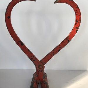 May include: A red metal log grabber with two handles. The grabber is shaped like a heart and has a distressed finish.