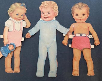 May include: Three paper dolls, one girl and two boys, with removable clothing. The girl is wearing a pink dress and a white blouse. One boy is wearing a blue jumpsuit. The other boy is wearing red shorts with a blue and white stripe.