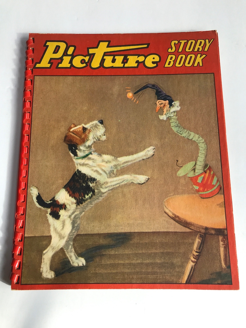 May include: A red and yellow book with the title "Picture Story Book" on the cover. The cover features an illustration of a white and brown dog jumping up to catch a ball thrown by a jester with a long green nose.