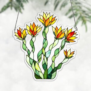 May include: A stained glass window hanging featuring a stylized floral design. The flowers have yellow and orange petals with green stems. The glass is outlined in white and hangs from a silver chain.