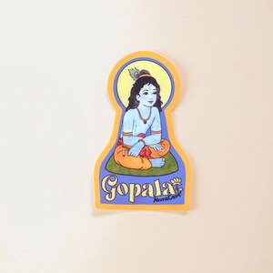 May include: A colorful sticker featuring a seated figure with blue skin, wearing orange and yellow clothing, and a peacock feather in their hair. The sticker has the word "Gopala" in a stylized font.