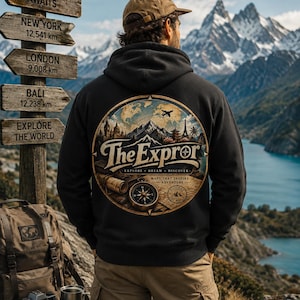May include: A black hooded sweatshirt featuring a large circular graphic on the back. The design includes a compass, a map, and landmarks with the text The Expror, Explore Dream Discover, and Maps That Inspire Adventure printed in a vintage style.