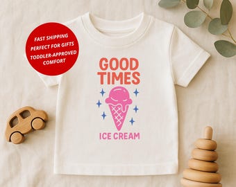 May include: A white toddler t-shirt featuring a pink ice cream cone graphic and the words "GOOD TIMES ICE CREAM" in pink and blue. A wooden toy car and a wooden stacking toy are in the image.