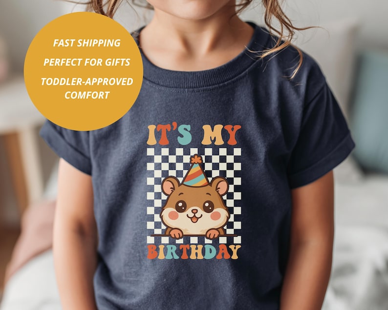 May include: Navy blue toddler t-shirt with a colorful graphic. The graphic features a cute cartoon bear wearing a party hat, set against a checkered background, with the text "IT'S MY BIRTHDAY".