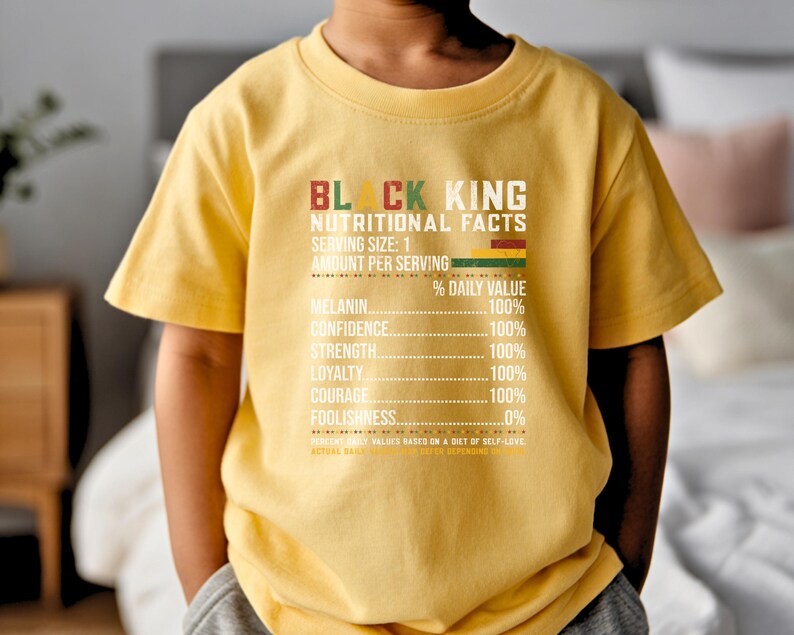 May include: A yellow t-shirt with the text "BLACK KING NUTRITIONAL FACTS" in red, green, and white. The shirt lists nutritional values for melanin, confidence, strength, loyalty, courage, and foolishness.