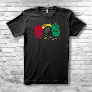 May include: Black t-shirt featuring a graphic of Bob Marley with the words "ONE LOVE" in red, yellow, and green brushstrokes. The design includes a portrait of Bob Marley and his signature.