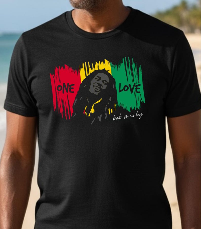 May include: Black t-shirt featuring a graphic of Bob Marley with the words "ONE LOVE" in red, yellow, and green. The design includes a portrait of Bob Marley and his signature.