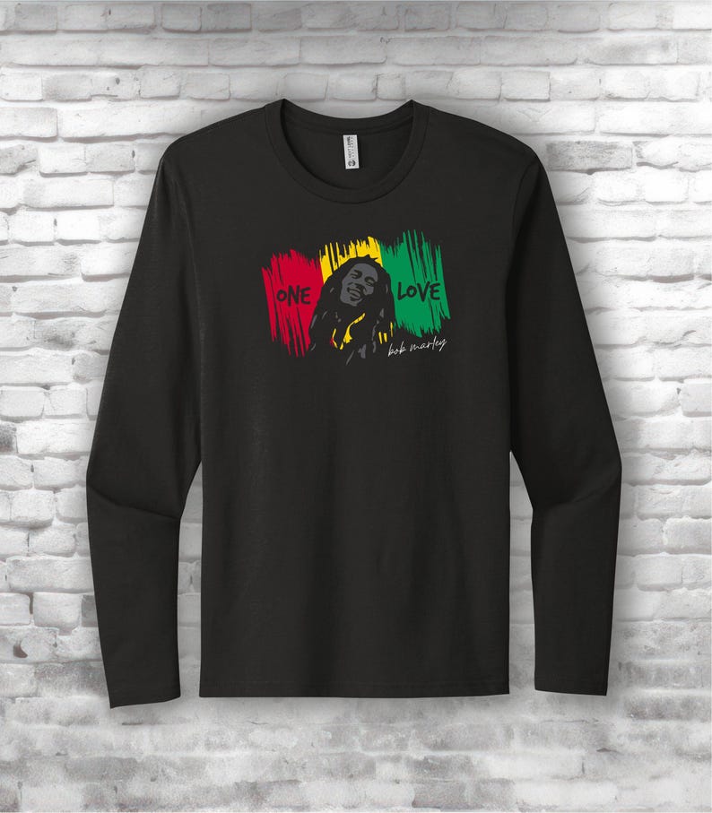May include: Black long-sleeve shirt featuring a graphic of Bob Marley with the words "ONE LOVE" in red, yellow, and green. The shirt has a crew neck and is made of a soft material.