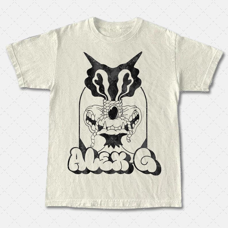 May include: A white t-shirt with a black and white graphic print of a creature with a large eye and the text "Alex G".