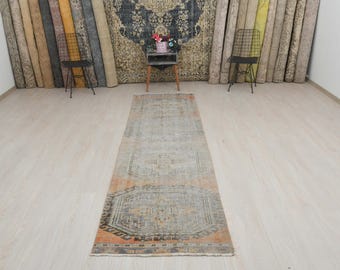 May include: A vintage runner rug with a faded blue and orange geometric pattern. The rug has a distressed look and is perfect for adding a touch of bohemian style to any room.