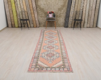 May include: A long, narrow runner rug with a peach background and a floral pattern in shades of pink, green, and blue. The rug has a fringe border.