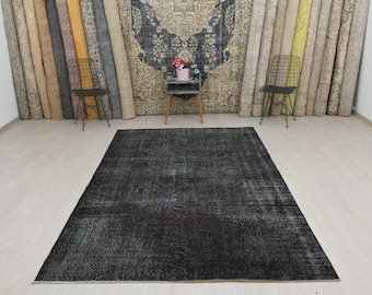 May include: A black vintage rug with a distressed look. The rug has a faded, worn appearance, giving it a unique and rustic charm.