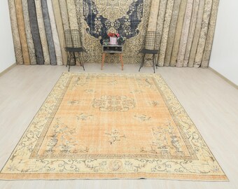 Op de afbeelding: Een groot, rechthoekig vloerkleed in vintage stijl, in oranje en crème. Het heeft een centraal medaillonontwerp en een gedetailleerde rand met bloemen- en geometrische patronen. Het kleed ligt op een lichtgekleurde houten vloer. Afmetingen ca. 300 cm x 200 cm.