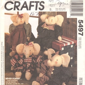 Op de afbeelding: McCall's Crafts patroon 5497 voor vier knuffelolifanten. De envelop bevat tekst en illustraties van de poppen in verschillende outfits met rood, wit en blauwe patronen. De tekst vermeldt dat de poppen 40 cm lang zijn.
