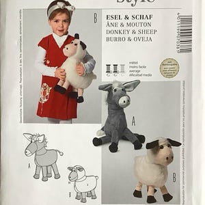 May include: A Burda Style sewing pattern with illustrations of a donkey and sheep, and a photo of a child holding a stuffed toy. The pattern includes text in multiple languages, including English and German.