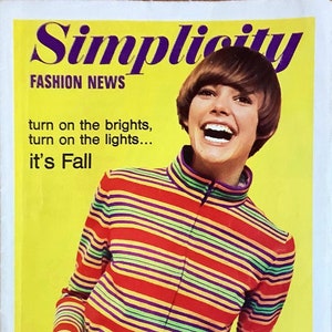 May include: A magazine cover featuring a woman wearing a colorful striped sweater and red pants. The magazine is titled "Simplicity Fashion News" and the text "turn on the brights, turn on the lights... it's Fall" is printed below the title. The magazine cover also features the number "7313" and the text "FEATURING OCTOBER PATTERNS".