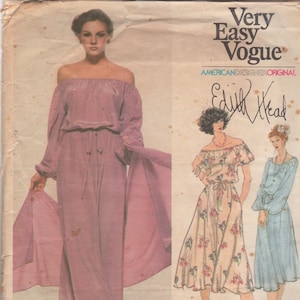 May include: Vintage Very Easy Vogue sewing pattern featuring a woman in a mauve off-the-shoulder jumpsuit with a matching scarf. The pattern also includes illustrations of two other dress designs. The pattern is labeled "American Designer Original" and signed by Edith Head.