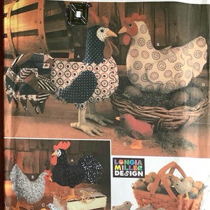 Op de afbeelding: Simplicity Crafts patroon met stoffen kip- en haanontwerpen. De afbeelding toont een haan met een patchwork ontwerp en een hen met een wit en rood cirkelpatroon. Extra afbeeldingen tonen kuikens en een mand met eieren.
