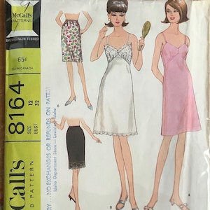 May include: Vintage McCall's sewing pattern for a set of slips. The pattern is for sizes 12 and 32 bust. The pattern includes three different styles of slips: a white slip with lace trim, a pink slip, and a black slip with lace trim. The pattern is labeled "Misses' Set of Slips".