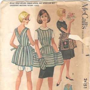 May include: A vintage sewing pattern for a wrap-around cobbler apron, half apron, and mitt. The pattern is from McCall's and is printed on a light brown paper with a blue and white striped design. The pattern includes instructions for sizes 10-12.