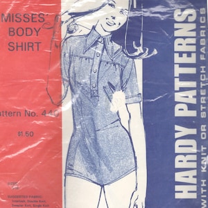 May include: A vintage sewing pattern for a misses' body shirt. The pattern is for use with knit or stretch fabrics. The pattern number is 440 and the price is £1.50. The suggested fabric is interlock, double knit, or sweater knit. The pattern includes instructions for notions such as fusible interfacing, snaps, and buttons.