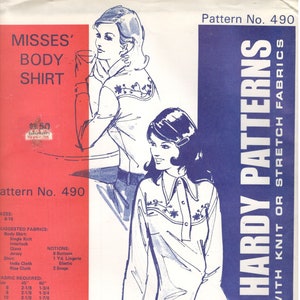 May include: A sewing pattern for a women's body shirt with a blue and white floral embroidery design. The pattern is from Jean Hardy Patterns and is for use with knit or stretch fabrics. The pattern number is 490.