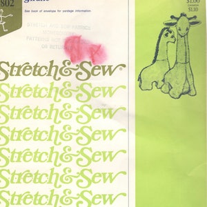 May include: A vintage sewing pattern featuring two giraffes in a green and white color scheme. The pattern is titled "Stretch & Sew" and is designed exclusively for knit fabrics by Ann Person. The pattern number is 091975.