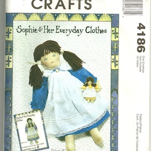May include: A sewing pattern for making a ragtime doll named Sophie and her clothes. The pattern features a doll with brown hair, a blue and white dress, and a smaller doll with yellow hair and a white dress. The pattern is titled "Sophie & Her Everyday Clothes" and is part of McCall's Crafts.