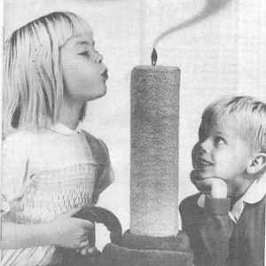 May include: A black and white photo of two children playing with a towel shaped like a candle. The towel candle is lit and has a plume of smoke coming from the top. The text "Make it with Towels!" is in a speech bubble above the children. The text "Cannon Homemaking Service" and "1271 Avenue of Americas, New York, N. Y. 10020" is at the bottom of the image.