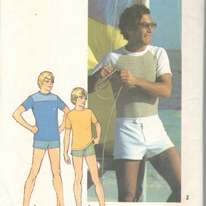 Op de afbeelding: Simplicity naaipatroon 7550 met illustraties van heren tops en shorts. Het patroon bevat een blauwe top, een gele top en een gestreepte top met een witte short. De tekst "TOPS SIZED FOR STRETCH KNITS ONLY" is zichtbaar.