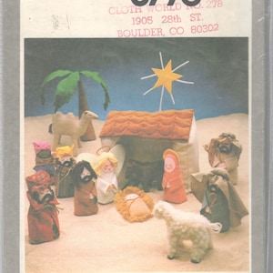 May include: A Simplicity pattern for a nativity scene, featuring a camel, a star, a stable, and figures of Mary, Joseph, the baby Jesus, an angel, and three wise men. The pattern number is 8776, and the title is "Cloth World No. 278".