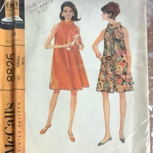 以下が含まれることがあります： ミセス用ドレスのヴィンテージMcCall's印刷パターン、サイズsmall 10-12。パターンは、オレンジ色と花柄の2つのドレスデザインを特徴としています。パターンには「Easy to Sew」と書かれています。
