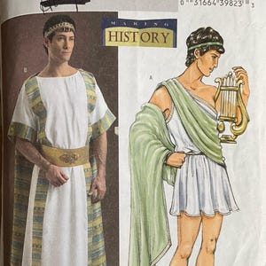 May include: Butterick sewing pattern B4573 for historical costumes. The package displays two outfits: a long white tunic with patterned trim and a gold belt, and a shorter white tunic with a green drape, a gold lyre, and black gladiator sandals.