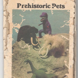 May include: Vintage sewing pattern titled "Prehistoric Pets" featuring illustrations of plush dinosaurs and a woolly mammoth. The pattern cover is aged with torn edges and the text "Buttenck" is visible at the top.