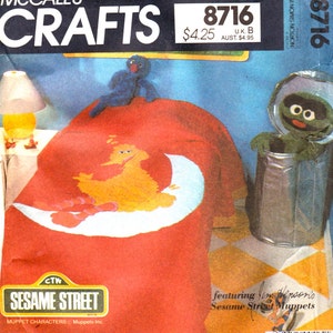 May include: A red, orange, and white Sesame Street applique featuring Big Bird and the moon. The applique is on a red bedspread. The pattern is for a craft project to make a bedspread with a Sesame Street theme.