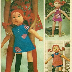 Op de afbeelding: Drie handgemaakte ragdolls met rood haar en vlechtjes. De poppen dragen verschillende jurken. Eén pop draagt een blauwe jurk met witte stippen, een andere draagt een roze jurk met witte bloemen en de derde draagt een rood-wit gestreepte jurk.