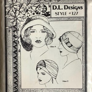 May include: A black and white illustration of three vintage hat designs, labeled "View A" and "View C". The top right corner reads "D.L. Designs STYLE #127". The image is framed with a decorative border and floral accents.