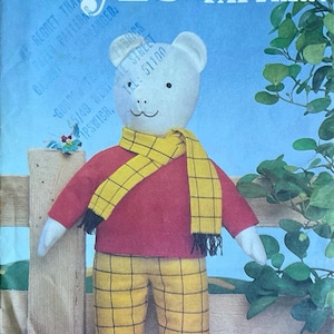 Può includere: Una copertina di modello artigianale vintage con un orsacchiotto che indossa una camicia rossa, pantaloni a quadri gialli e una sciarpa gialla. L'orso ha la testa e le braccia bianche. Il testo "Style CRAFT PATTERN".