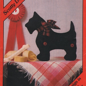 Könnte beinhalten: Ein Schnittmuster für eine schwarze Scotty Dog Weichskulptur von Yours Truly. Das Muster enthält Anweisungen für fünf Größen, von Mini (7.6cm x 8.9cm) bis groß (36.2cm x 30.5cm). Der Hund hat eine karierte Schleife und Knöpfe.