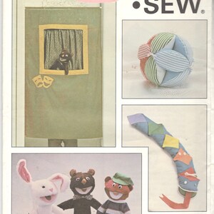 May include: A sewing pattern for making a puppet show stage, a ball toy, a snake toy, and three hand puppets. The puppets are a rabbit, a bear, and a person with a striped shirt and a green hat. The pattern is from Kwik Sew Pattern Co., Inc. and is number 1217.