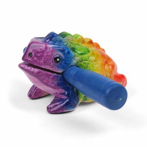 May include: A rainbow coloured frog shaped wooden percussion instrument with a blue mallet. The frog has a cracked paint finish and a textured surface.