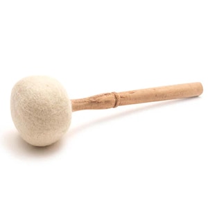 Op de afbeelding: Een witte vilt hamer met een houten steel. De hamer wordt gebruikt om instrumenten zoals gongs en klankschalen te slaan.