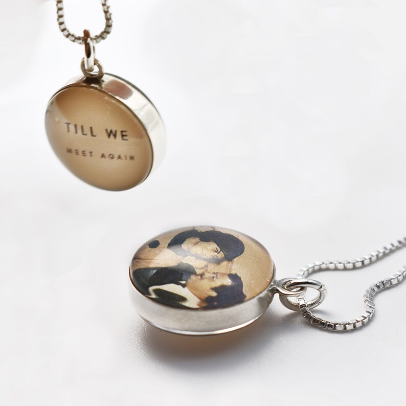 May include: Two silver pendant necklaces. One pendant features a photo of a couple, the other pendant has the text "Till We Meet Again".