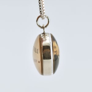May include: A silver necklace with a round pendant featuring a vintage photo of a woman. The pendant is double-sided, with the other side showing the text "TILLY STREET A".