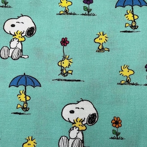 May include: A turquoise fabric with a repeating pattern of Snoopy and Woodstock. Snoopy is depicted hugging Woodstock, while Woodstock is holding an umbrella, a flower, and walking alone. There are also purple and orange flowers in the pattern.