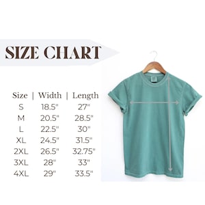 Puede incluir: Una camiseta verde agua cuelga de una percha de madera. Se muestra una tabla de tallas con medidas en pulgadas de ancho y largo, desde la talla peque&ntilde;a hasta la 4XL. Las dimensiones de la camiseta se indican con flechas.