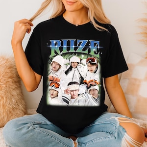 May include: Black t-shirt featuring a graphic of seven people in winter gear, with the word "RIZE" in a stylized font. The image has a vintage, retro aesthetic, with a green and blue lightning bolt design.