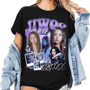 May include: Black t-shirt featuring a purple graphic with the word "JIWOO" and images of several women. The design includes butterflies and the word "nmixx" in a cursive font. The shirt is a casual style.