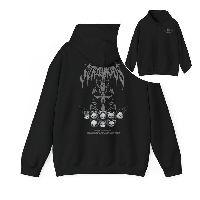 Puede incluir: Sudadera con capucha negra con un dise&ntilde;o gr&aacute;fico en la espalda. El dise&ntilde;o incluye el texto "Stray Kids" en una fuente g&oacute;tica y caras de animales estilizadas. La sudadera tiene un bolsillo delantero y una capucha.